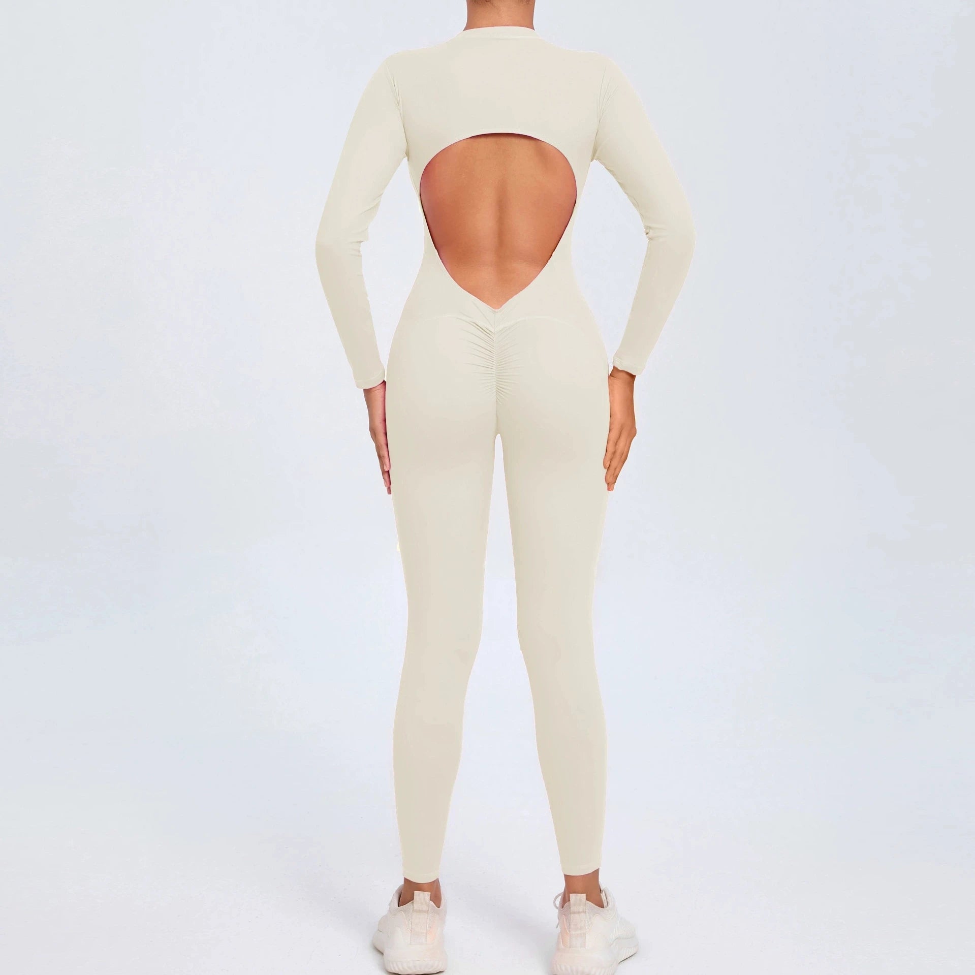 Beige backless long sleeve sports jumpsuit with front zipper designed for extreme comfort and confidence in the gym by allowing you to show off that pumped back