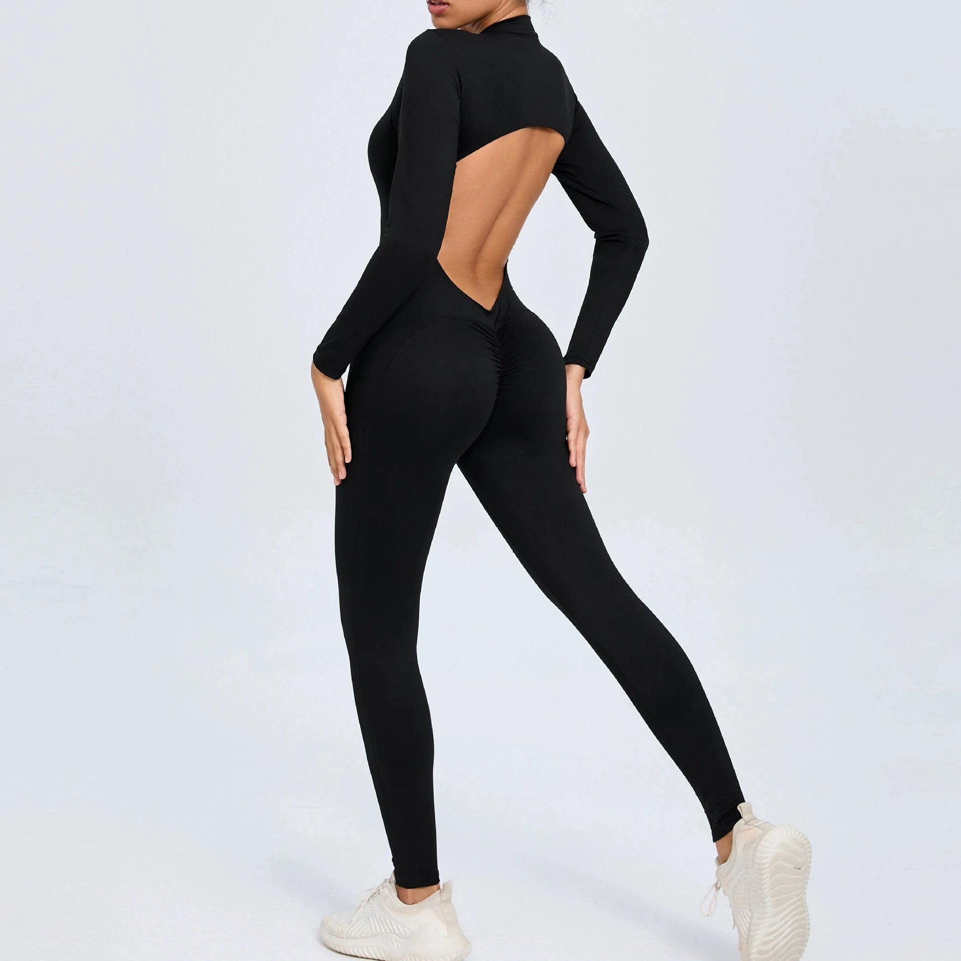 Black backless long sleeve sports jumpsuit with front zipper designed for extreme comfort and confidence in the gym by allowing you to show off that pumped back
