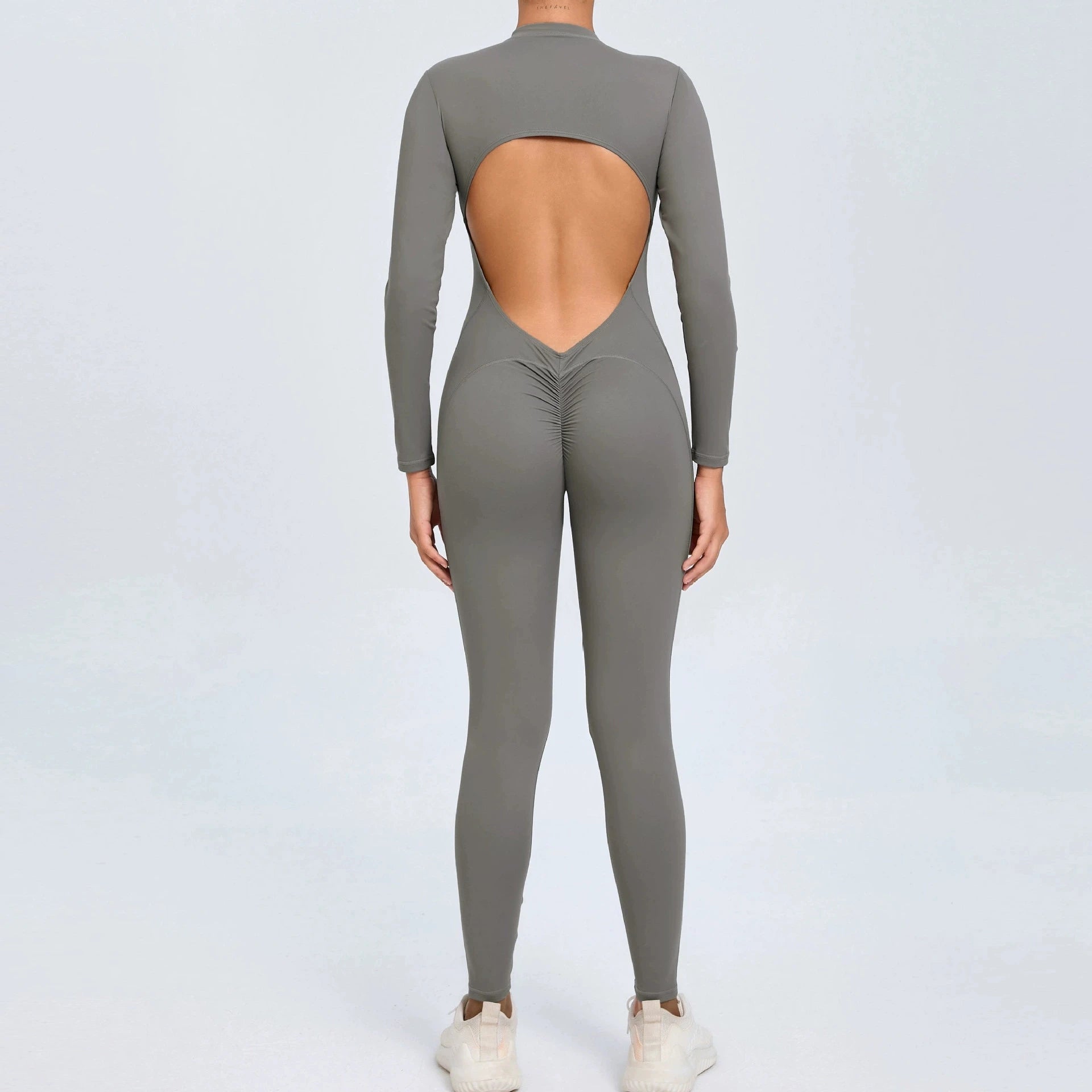 Grey backless long sleeve sports jumpsuit with front zipper designed for extreme comfort and confidence in the gym by allowing you to show off that pumped back